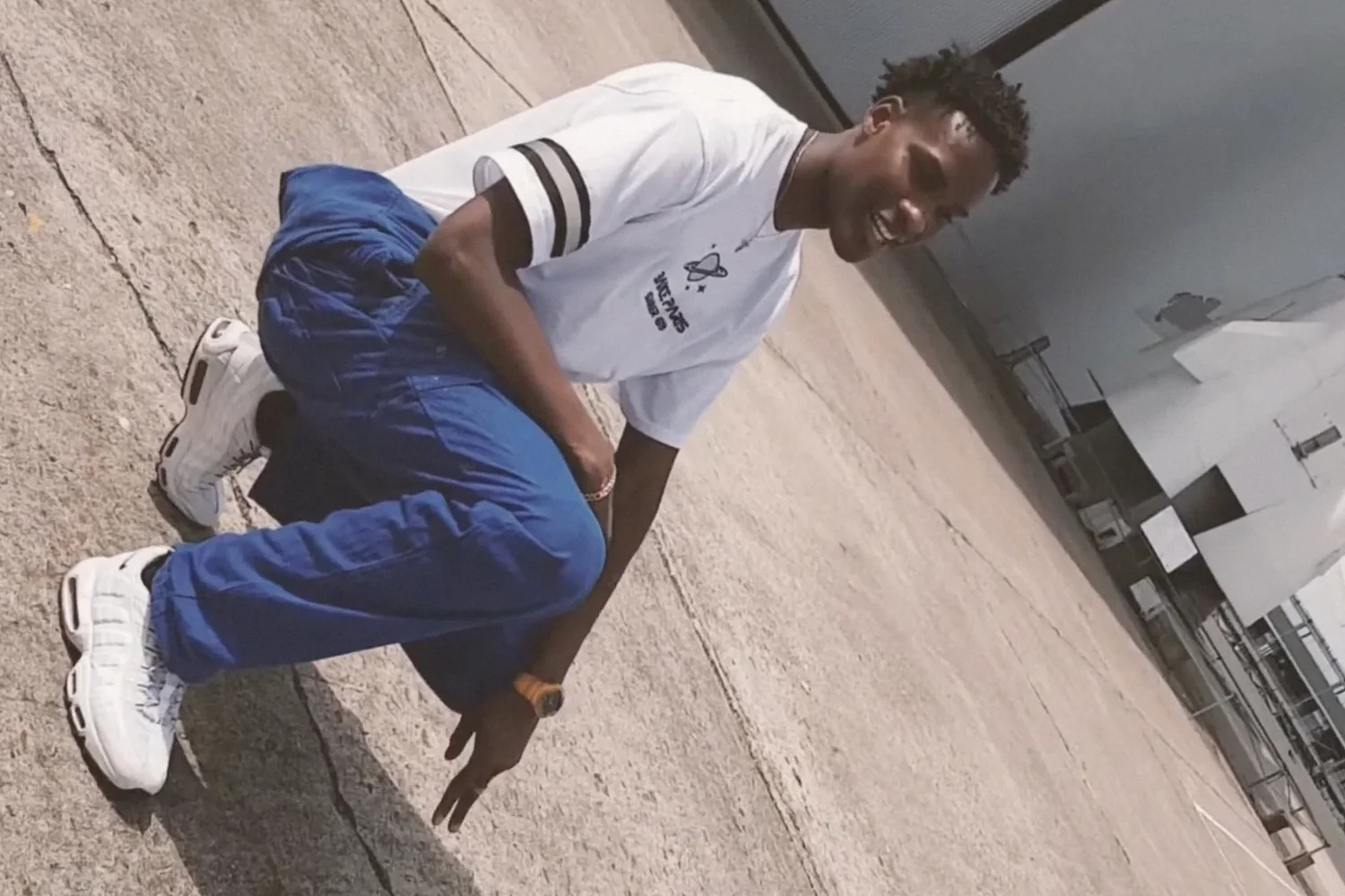 Summer 69, 2019 : t-shirt Bance Paris et pantalon bleu, accroupi sur le tarmac devant une fusée